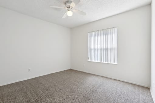 an empty living room with a ceiling fan and a window