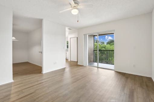 an empty living room with a sliding glass door to a balcony