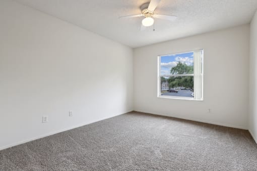 an empty room with a window and a ceiling fan