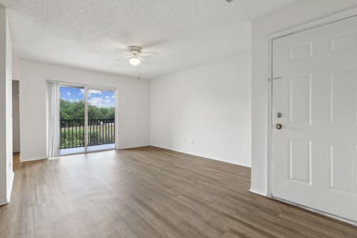 an empty living room with a door to a balcony