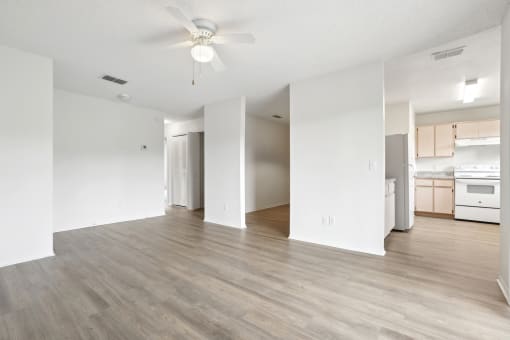 an empty living room and kitchen with a ceiling fan