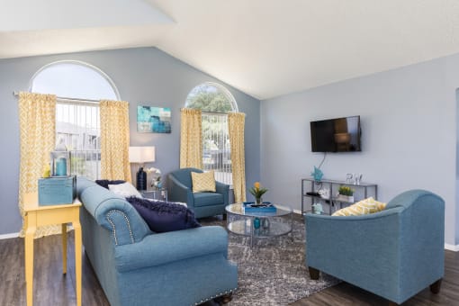 a living room with blue couches and chairs and a tv