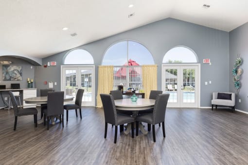 a dining room area with a table and chairs and large windows