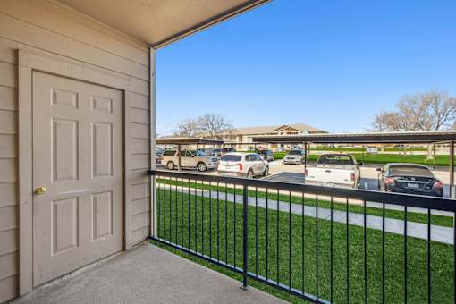 A view from a balcony with a white door and a black railing.