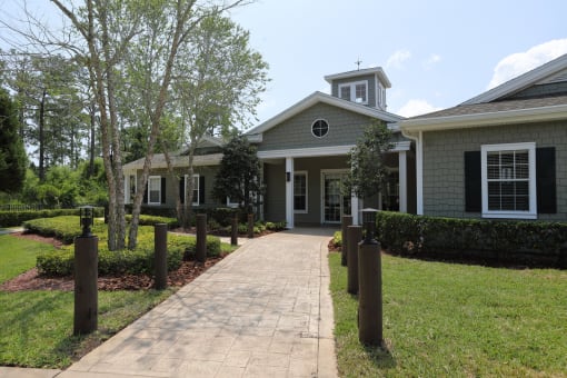 The Management Office is a nautical styled building with shingle siding in dark grey and blue colors. The brick paver walkway up to the front doors are lined with wooden harbor posts.