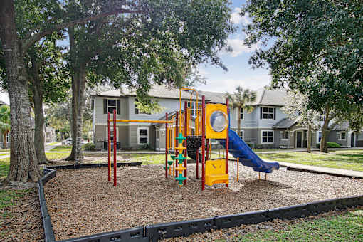 A playground with a yellow slide and a blue tarp.