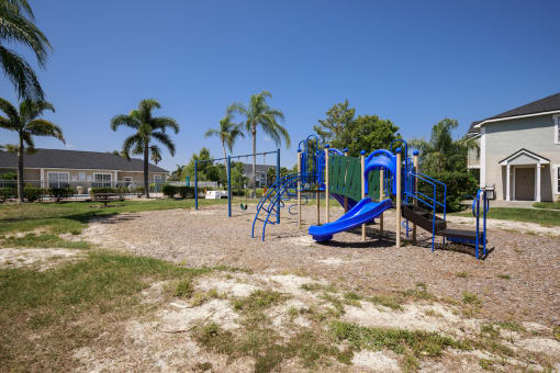 Playground on Mulch in Grassy Courtyard with Building Exterior in the Background Next to Fenced in Pool