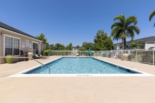 Swimming Pool and Sun Deck with Lounge Chairs with Trees and Building Exteriors in the Background