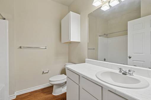 A white bathroom with a toilet, sink, and mirror.