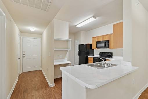 A kitchen with white countertops and wooden cabinets.