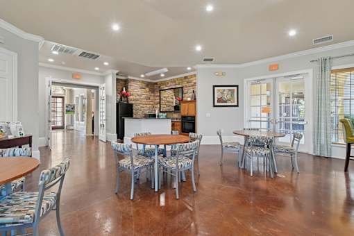 A clubhouse lounge area with wooden tables surrounded by chairs.