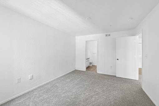 A spacious room with white walls and carpeted floor.