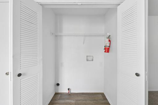 A white room with a fire extinguisher on the wall.