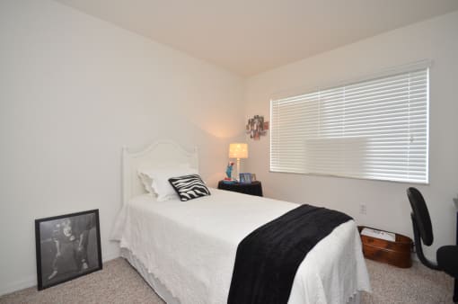 a bedroom with white walls and a white bed with a black and white pillow