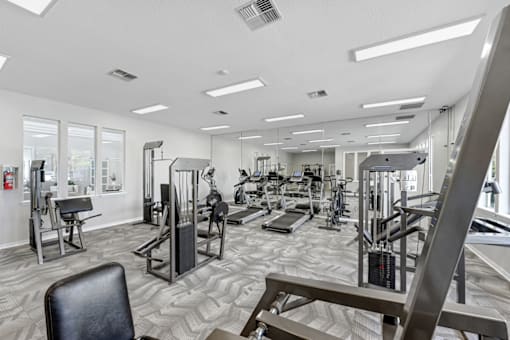 a spacious fitness center with cardio machines and other exercise equipment