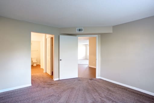 a bedroom with a carpeted floor and an open door to a bathroom