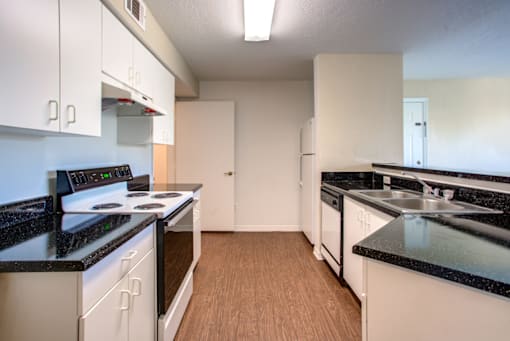 a kitchen with white cabinets and black countertops