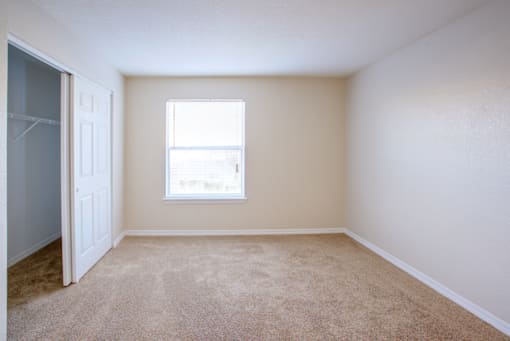 an empty bedroom with a closet and a window