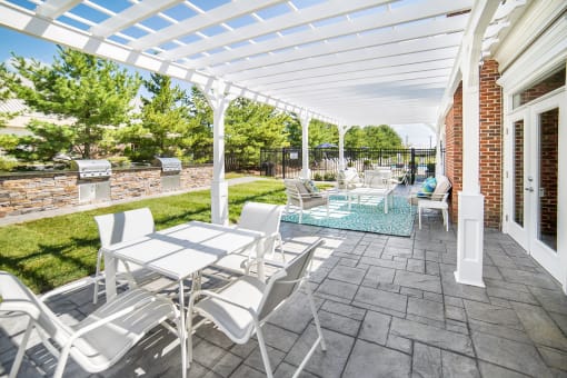a pergola over a patio with tables and chairs
