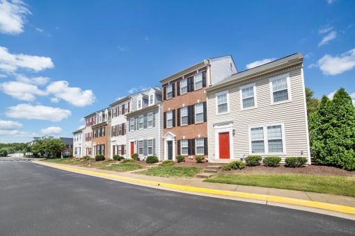 a row of townhomes on a sunny day with a street in the foreground