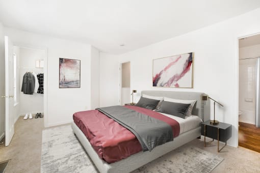 a bedroom with white walls and a gray bed with a red blanket