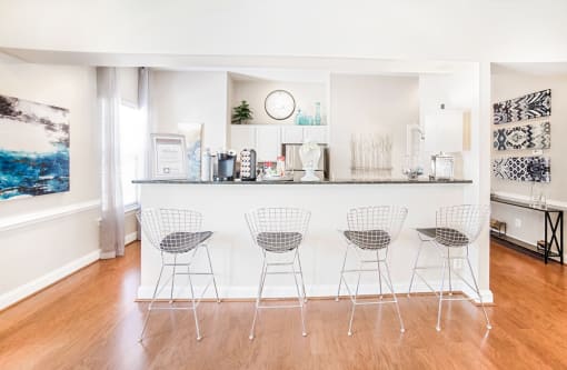 a kitchen with white appliances and a bar with four stools