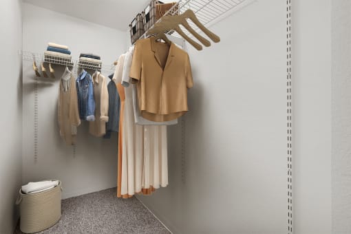a walk in closet with a coat rack and clothes hanging on the wall