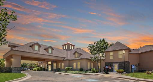 Clubhouse exterior at sunset with dormer windows at Rose Cove Homes Apartments, Farmington, UT 84025