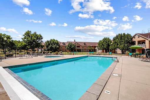 Outdoor swimming pool with sundeck and lounge chairs at Rose Cove Homes Apartments, Farmington