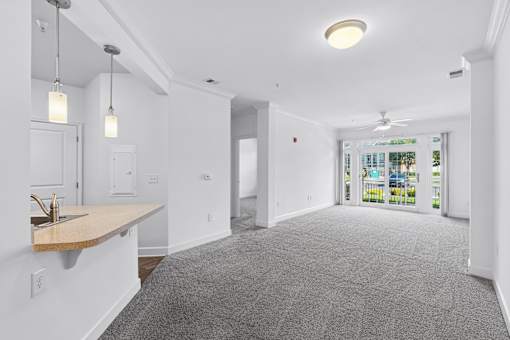 A spacious room with a carpeted floor and a ceiling fan.