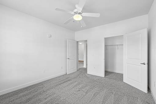 A room with a ceiling fan and carpeted floor.