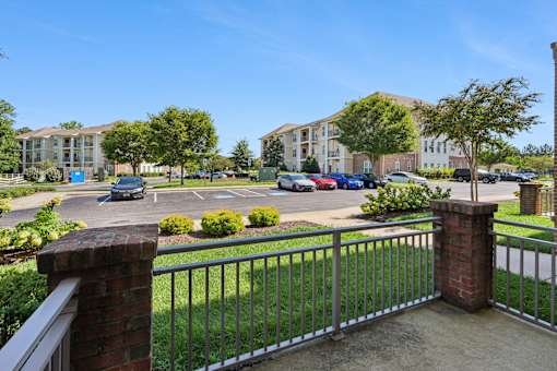 A view of a parking lot from a balcony with a metal railing.