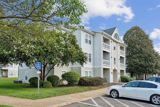A white car is parked in a parking lot in front of a building.