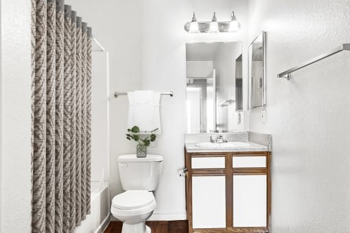 bathroom with white cabinets and hardwood-style flooring