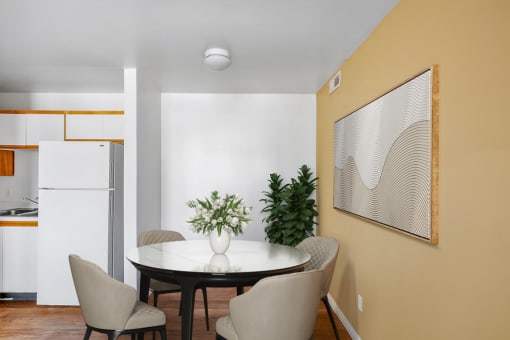 Virtually staged dining area with dining table and chairs, wall art, wooden floors and tan walls