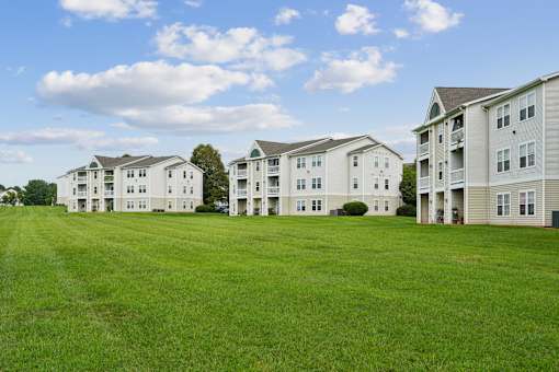 A row of apartment buildings with green lawns in front.