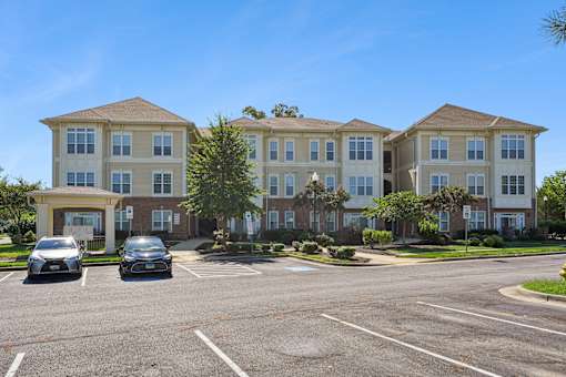 A large apartment complex with a parking lot in front.