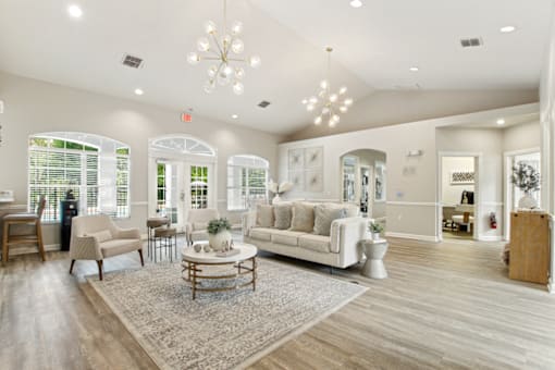 A spacious living room with a white sofa, wooden coffee table, and a chandelier.