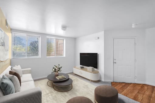 Virtually staged livingroom with couch, wall art, accent rug, coffee table, decorative seating, television on tv stand, two windows, carpet, tan accent wall, and wooden entry way