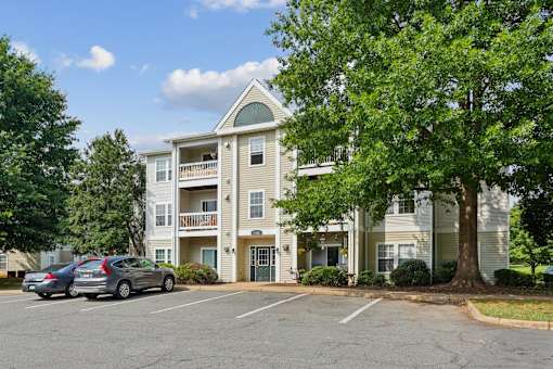 A large apartment building with a parking lot in front.