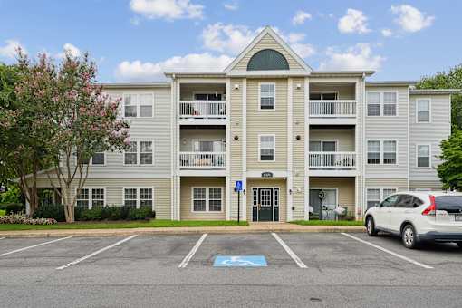 A white car is parked in a parking lot in front of a building.