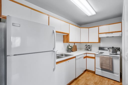 Virtually staged kitchen with pot on stove, white appliances and wooden floors