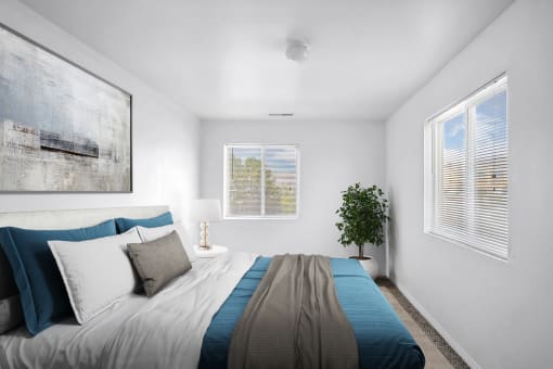 Virtually staged bedroom with bed, wall art, side table with lamp, potted plant, white walls and carpet with two windows