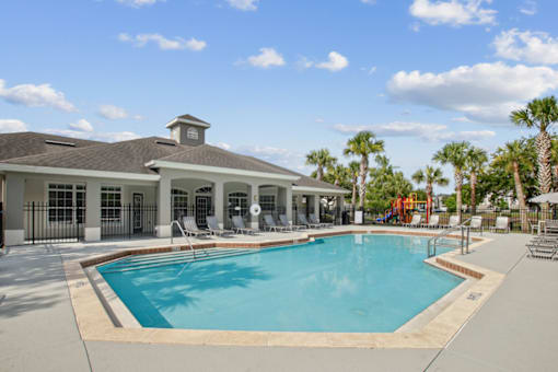A large swimming pool in front of a building with a black fence around it.
