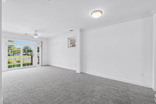 A room with a grey carpet and a ceiling fan.