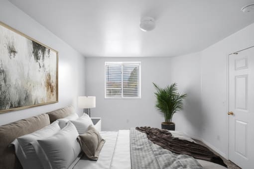Virtually staged bedroom with bed, wall art, side table with lamp, potted plant, carpet and white walls and window