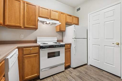 A kitchen with white appliances and wooden cabinets.