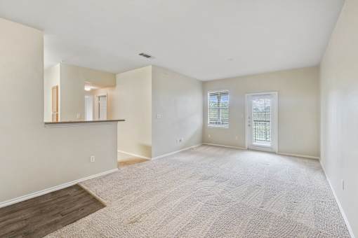 A spacious room with a carpeted floor and a window with blinds.