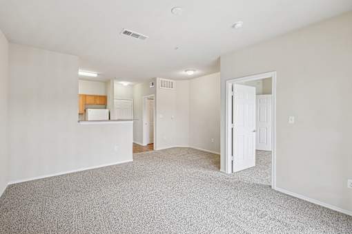 A spacious room with a carpeted floor and a door on the right side.