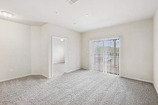 A spacious room with a carpeted floor and a sliding glass door.